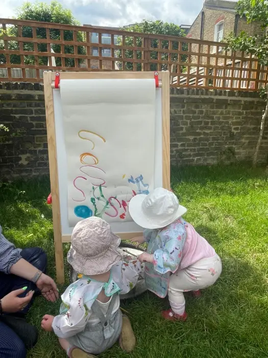 Children painting at an easel in the garden