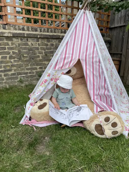 A child reading in a teepee in the garden