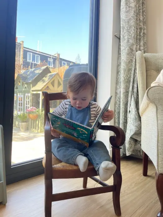 A child reading in a small armchair by the window