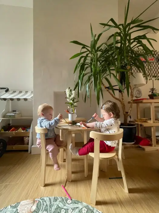 Two children sitting at a small table in the classroom