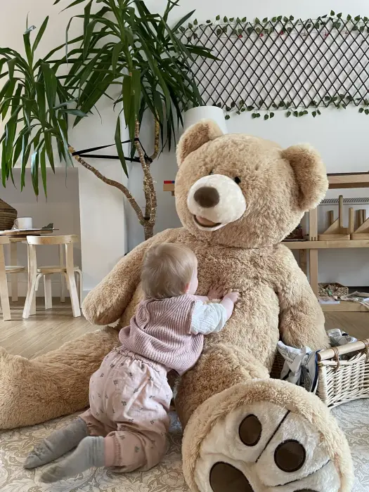 A child cuddling a giant teddy bear